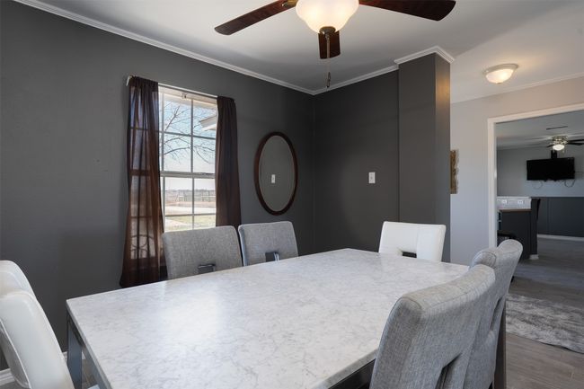 Dining space with ceiling fan, wood finished floors, ornamental molding, and baseboards | Image 10