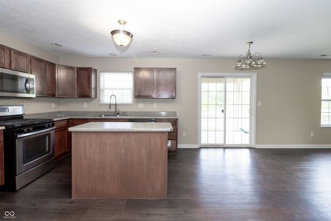 kitchen featuring stainless steel appliances, a chandelier, light countertops, and plenty of natural light | Image 10