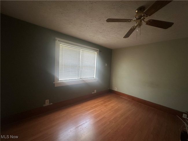 Empty room featuring light wood-type flooring, a textured ceiling, a ceiling fan, and baseboards | Image 11