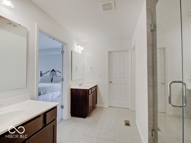 ensuite bathroom featuring full shower, two vanities, ceramic tile floors & 2 walk-in closets | Image 34