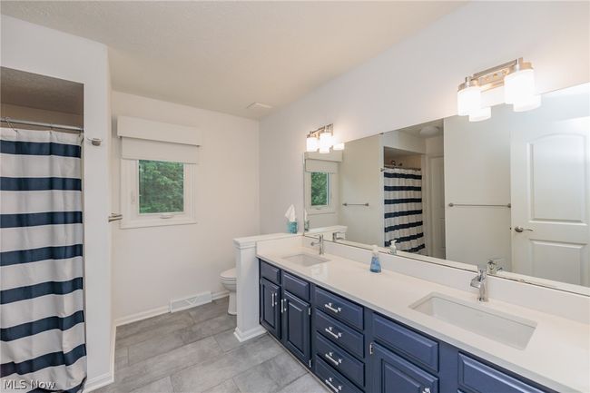 Bathroom with tile floors, dual bowl vanity, a healthy amount of sunlight, and toilet | Image 32