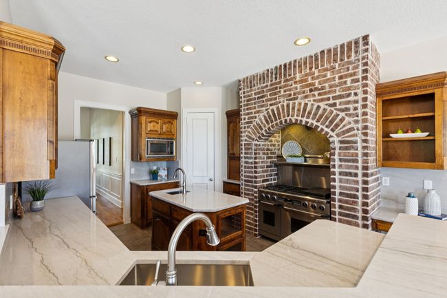 Breathtaking kitchen with newly installed granite countertops with slab backsplash. The stone housing area with commercial gas range with dual fuel double ovens is a culinary delight. Additional features are the appliance garage, prep sink in the island and large walk in pantry. | Image 11