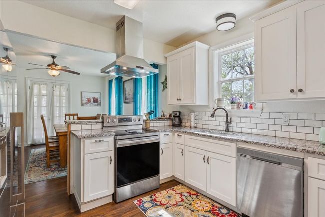 Kitchen with wall chimney exhaust hood, a sink, a ceiling fan, a peninsula, and stainless steel appliances | Image 12