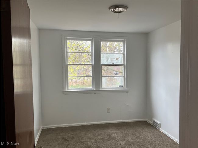 Unfurnished room with visible vents, dark colored carpet, and baseboards | Image 5