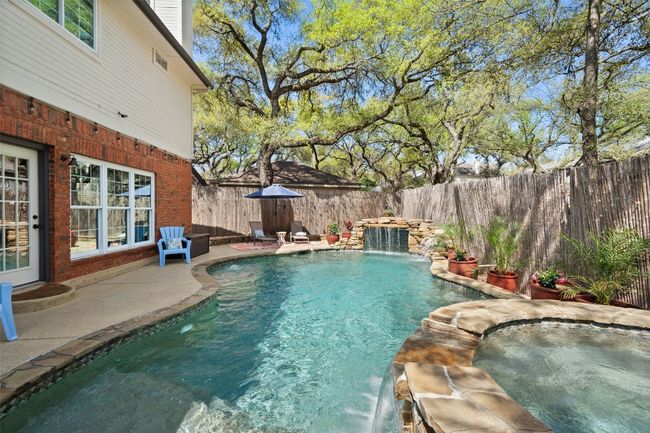 View of swimming pool with a fenced backyard, a pool with connected hot tub, and a patio area | Image 34