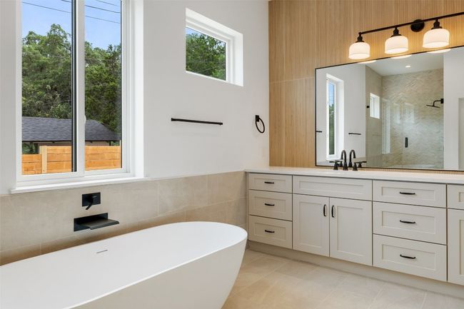 Bathroom featuring a shower stall, a freestanding bath, vanity, tile walls, and tile patterned floors | Image 16