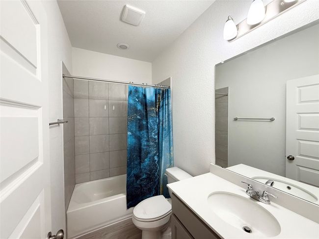 Bathroom featuring vanity, toilet, shower / bath combination with curtain, wood finished floors, and a textured ceiling | Image 19