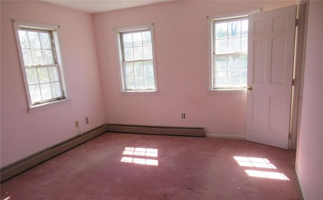 Unfurnished room with baseboard heating, plenty of natural light, and carpet floors | Image 7