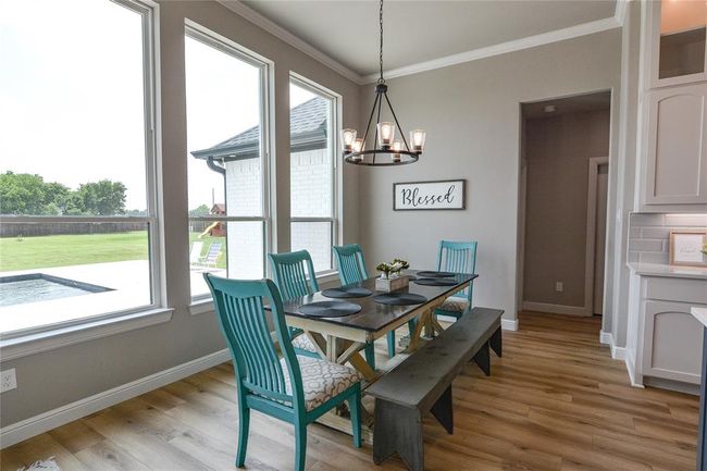 Dining space featuring a chandelier, light wood-style flooring, and crown molding | Image 13