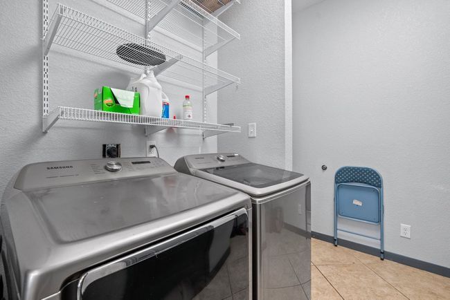 Laundry area with laundry area, baseboards, washer and clothes dryer, a textured wall, and light tile patterned flooring | Image 30