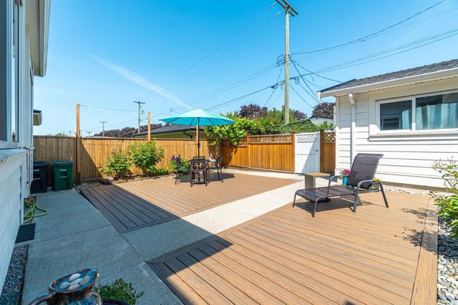 Wooden terrace with a fenced backyard and outdoor dining area | Image 19