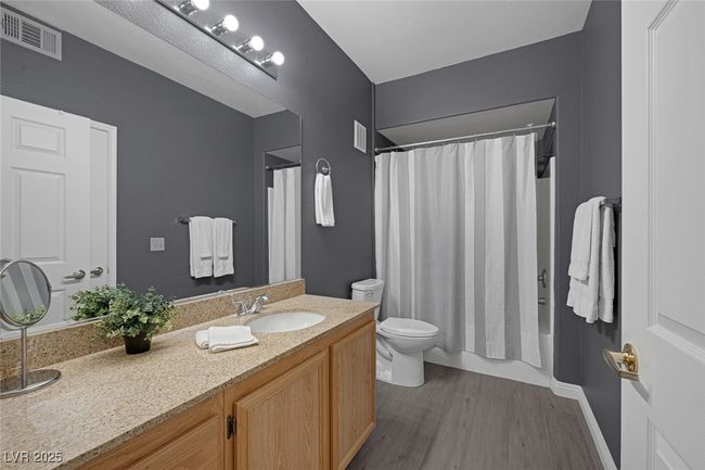 Full bath with visible vents, wood finished floors, vanity, toilet, and shower / tub combo with curtain | Image 20