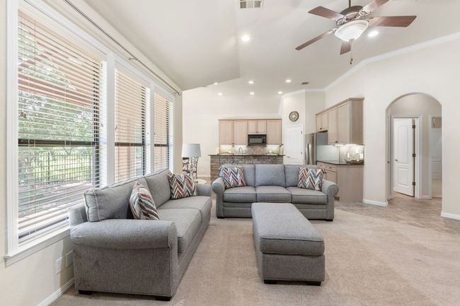 Living area with crown molding, arched walkways, ceiling fan, recessed lighting, and light colored carpet | Image 8