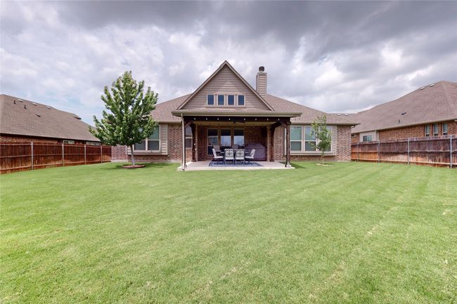 Back of house with brick siding, a chimney, a patio area, and a shingled roof | Image 35