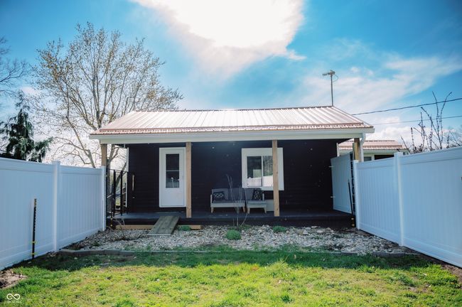 rear view of property featuring metal roof, fence, covered porch, and a lawn | Image 10