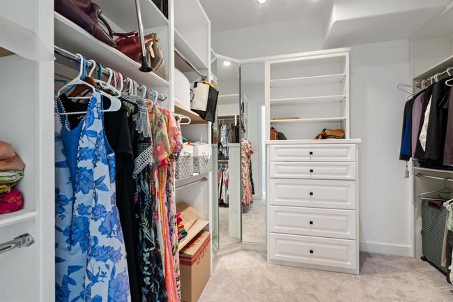 Spacious walk-in closet with built-in storage and shelves, offering ample room for organization. A full-length mirror adds both style and function. | Image 24