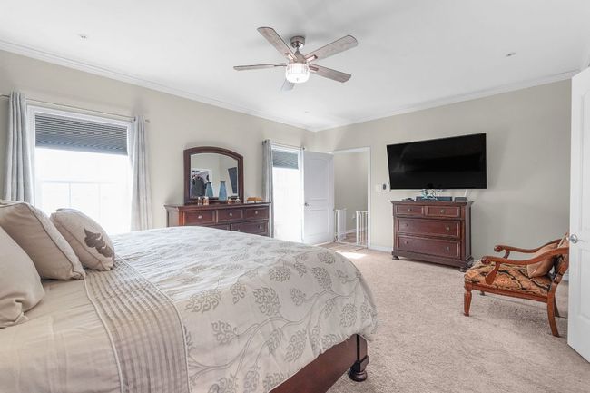 Bedroom featuring light colored carpet, baseboards, crown molding, and ceiling fan | Image 11