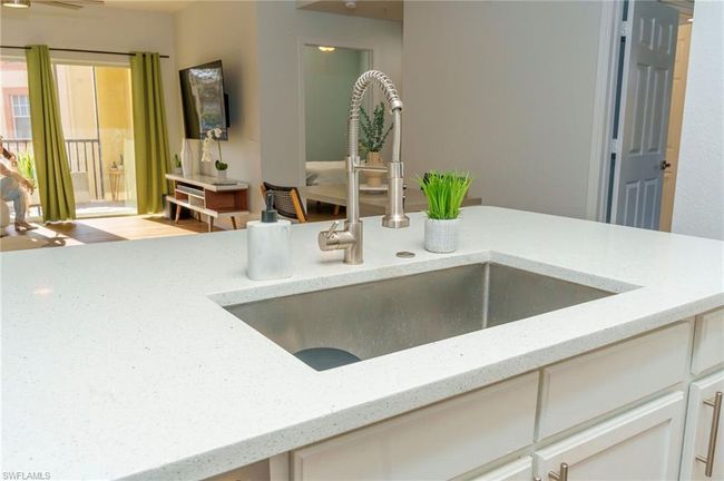 Interior details with light stone counters, a sink, and white cabinets | Image 9
