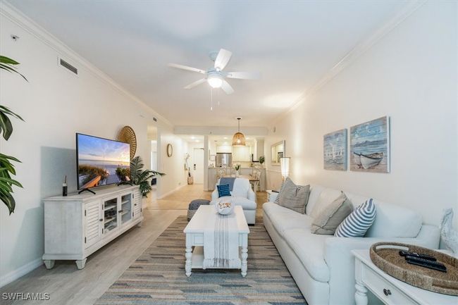 Living room with light hardwood / wood-style floors, ceiling fan, and ornamental molding | Image 8