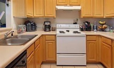 Kitchen with light tile flooring, sink, electric range, and dishwasher | Image 3