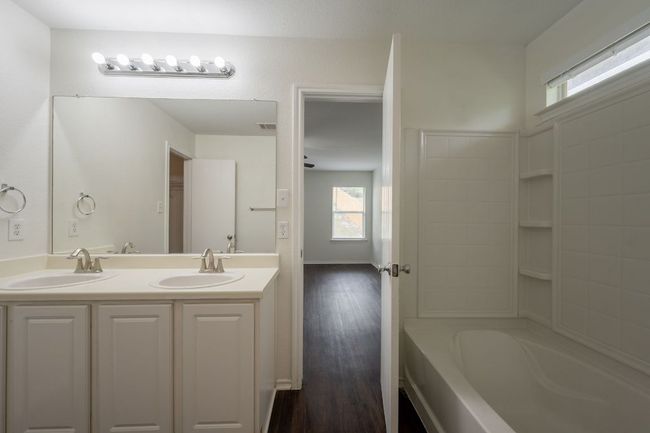 Bathroom with healthy amount of natural light, double vanity, wood finished floors, and shower / bath combination | Image 19