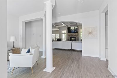 Open foyer and living room, den with a gas fireplace, light LVP floors, ornate columns, ceiling fan and coiffured ceiling | Image 3