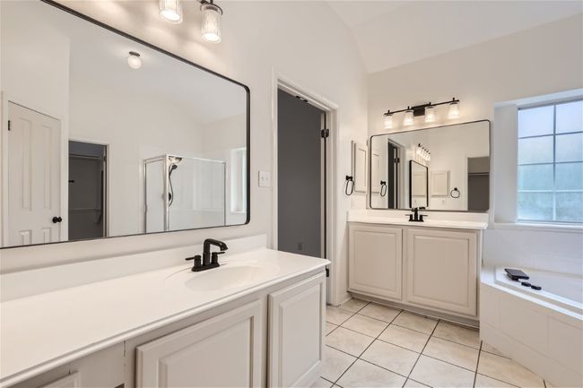 Bathroom with lofted ceiling, two vanities, a garden tub, tile patterned flooring, and a shower stall | Image 21