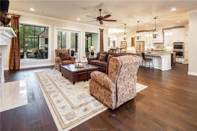 Living area featuring ornamental molding, ceiling fan with notable chandelier, recessed lighting, and dark wood-style floors | Image 7