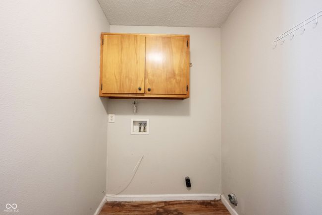 washroom with dark wood-style floors, baseboards, cabinet space, washer hookup, and a textured ceiling | Image 21