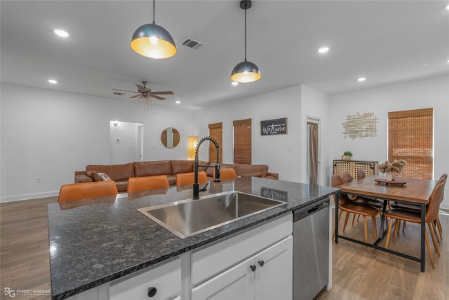 Kitchen featuring a sink, visible vents, stainless steel dishwasher, and light wood-type flooring | Image 12