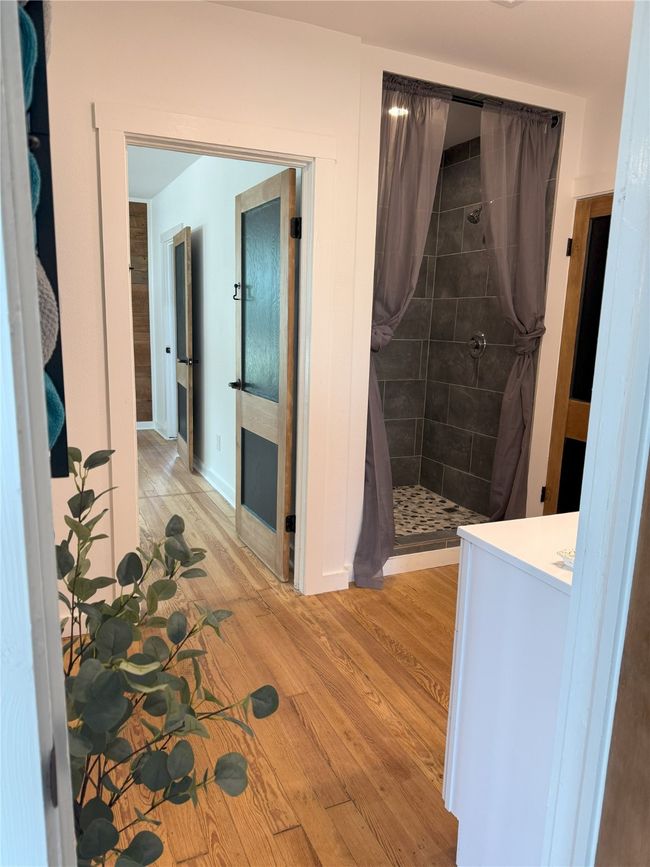 Full bath featuring a tile shower, wood finished floors, and vanity | Image 22