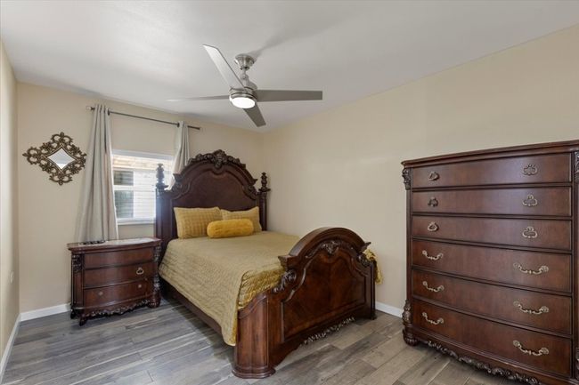 Bedroom with ceiling fan, light wood-type flooring, and baseboards | Image 16