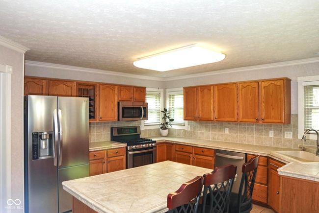 tile countertops, stainless steel appliances, and an island | Image 8