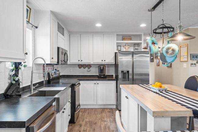 Kitchen with stainless steel appliances, open shelves, wooden counters, white cabinetry, and recessed lighting | Image 12