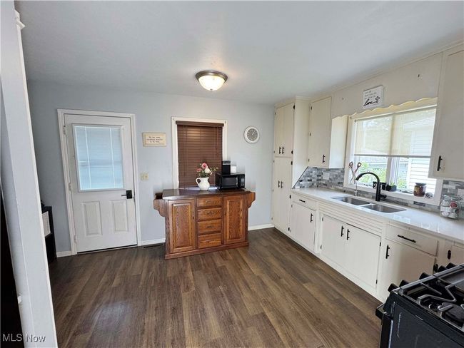 Kitchen featuring dark wood-style floors, black appliances, backsplash, light countertops, and white cabinetry | Image 15