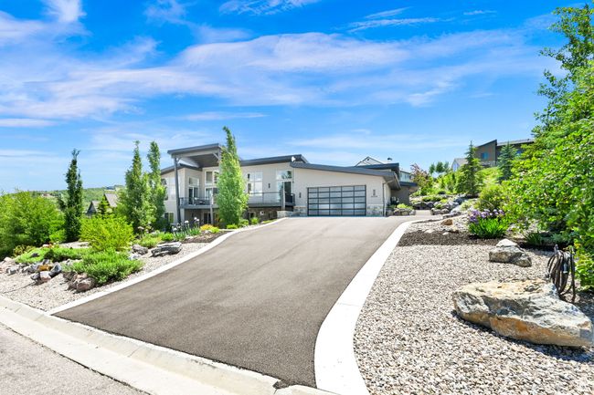 Contemporary home with stone siding, a garage, and asphalt driveway | Image 90