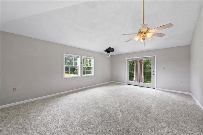Carpeted spare room featuring baseboards, vaulted ceiling, ceiling fan, and a healthy amount of sunlight | Image 61