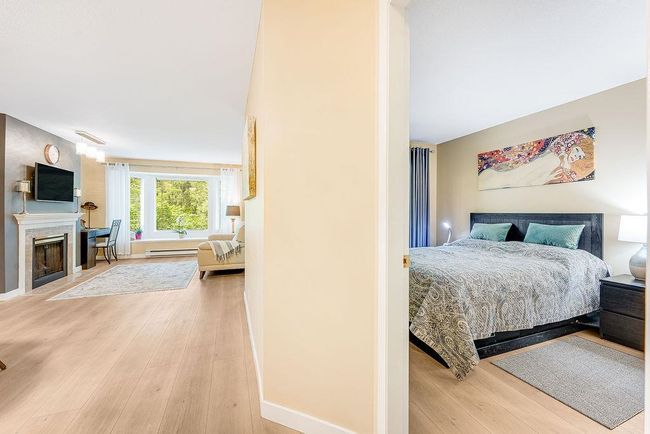 Bedroom featuring wood finished floors, a fireplace with flush hearth, and baseboards | Image 13