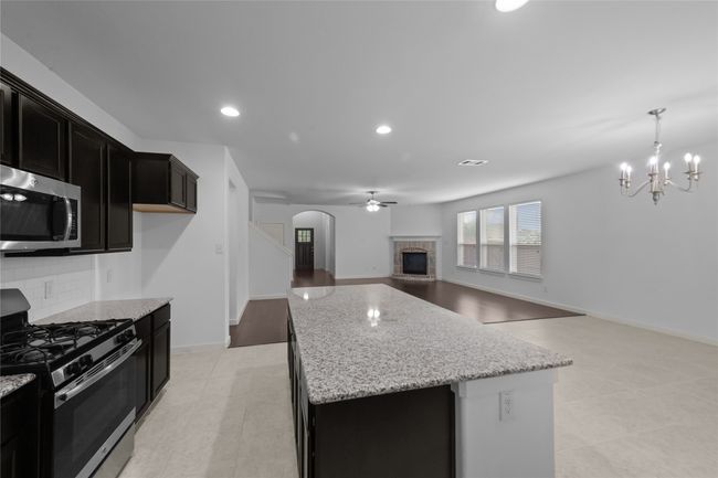 Kitchen featuring appliances with stainless steel finishes, arched walkways, a kitchen island, dark cabinets, and light stone counters | Image 16