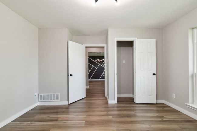 Unfurnished bedroom with wood finished floors, visible vents, and baseboards | Image 20