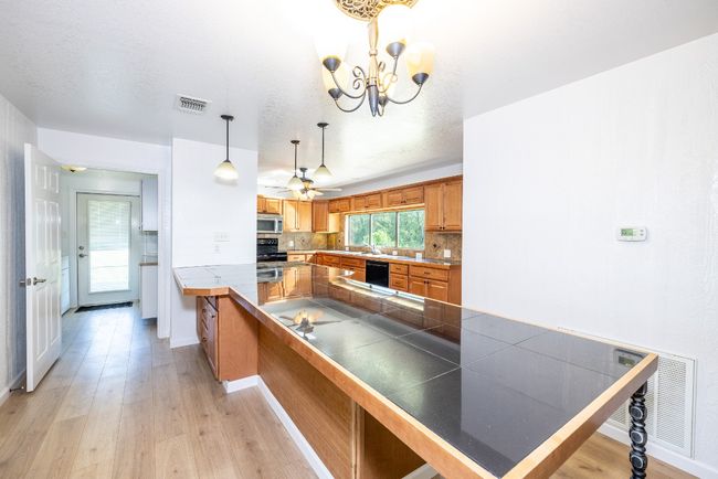 Kitchen with visible vents, stainless steel microwave, backsplash, and light wood-style floors | Image 7