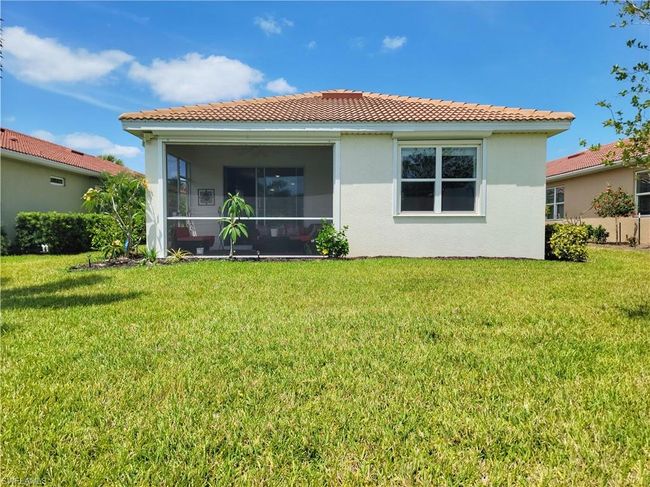 Rear view of house with a tile roof, a lawn, a sunroom, and stucco siding | Image 37