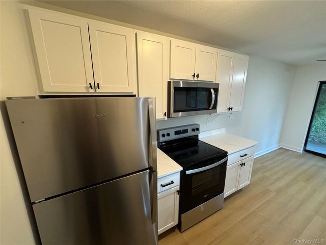 Kitchen featuring appliances with stainless steel finishes, light wood finished floors, white cabinets, and light stone countertops | Image 17