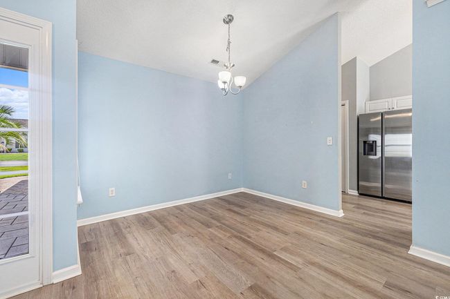 Spare room featuring a chandelier, light wood-style floors, and vaulted ceiling | Image 12