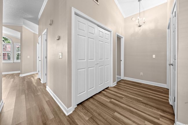 Hall featuring baseboards, a notable chandelier, ornamental molding, and wood finished floors | Image 15