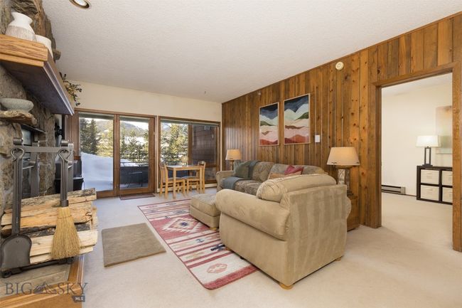 Living room with a textured ceiling, light colored carpet, a baseboard radiator, and wood walls | Image 22