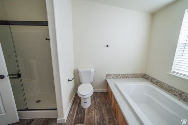 Full bath with toilet, wood finished floors, a stall shower, a bath, and baseboards | Image 14