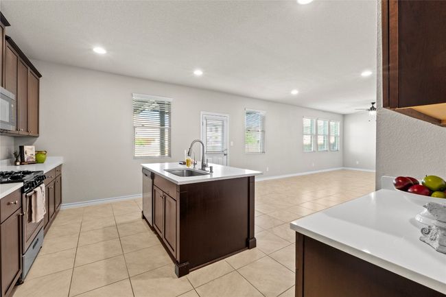 Kitchen featuring light tile patterned flooring, stainless steel appliances, light countertops, and a sink | Image 10