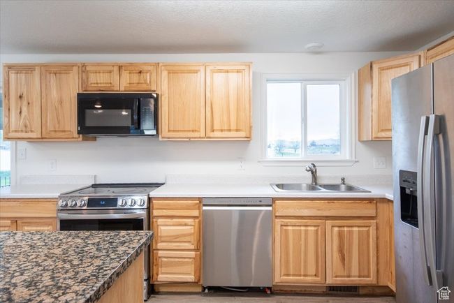 Kitchen featuring a sink, appliances with stainless steel finishes, light brown cabinetry, and a healthy amount of sunlight | Image 9