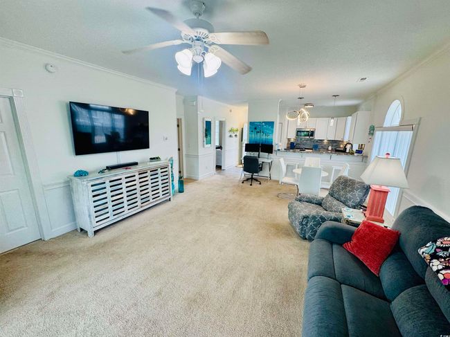 Living room with crown molding, light colored carpet, a ceiling fan, and a textured ceiling | Image 24